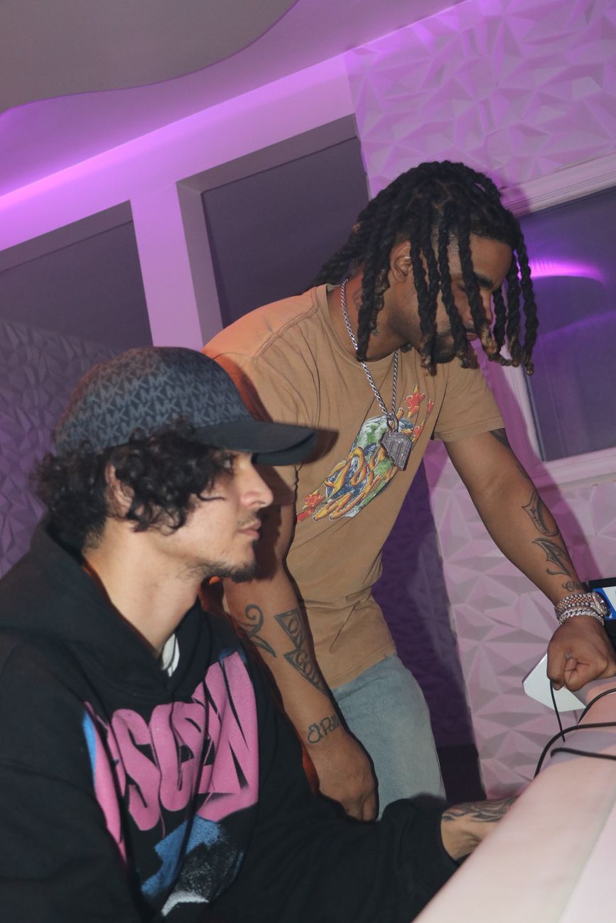 Producer working the board with an artist under purple light